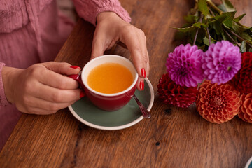 Women's hands hold a cup of sea buckthorn tea