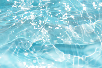 Blue water with ripples on the surface. Defocus blurred transparent blue colored clear calm water surface texture with splashes and bubbles. Water waves with shining pattern texture background.