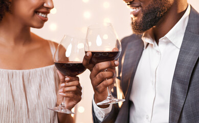 Black man and woman looking at each other and toasting with red wine, having dinner at restaurant, cropped