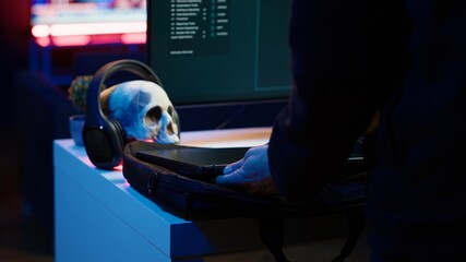 Hacker taking laptop out of suitcase, prepared to launch DDoS attack. Cybercriminal entering...
