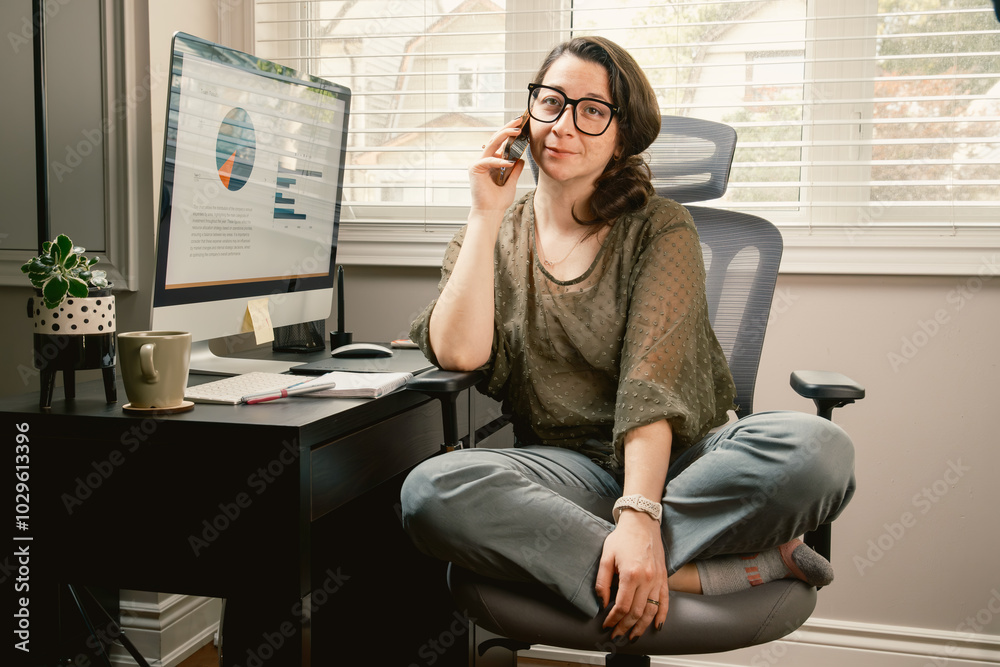 Wall mural a woman is sitting at a desk with a computer monitor and a cell phone