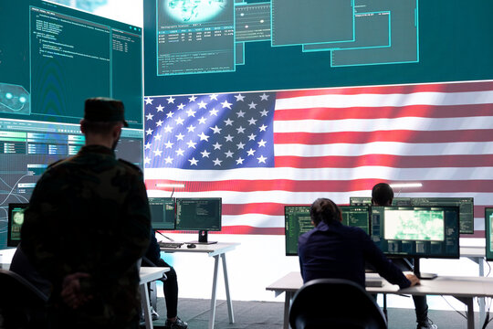 American army soldier working on servers and state secrets protection, safeguarding important hybrid war intelligence in high tech agency. Military official supervises hacking activity.