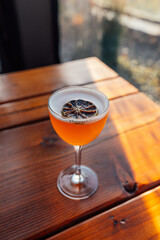 sour orange cocktail in nick and nora glass with dehydrated lime wheel garnish