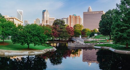 Fototapeta premium Pond in Marshall Park and downtown city skyline of skyscrapers at sunrise. Charlotte, North Carolina, United States.