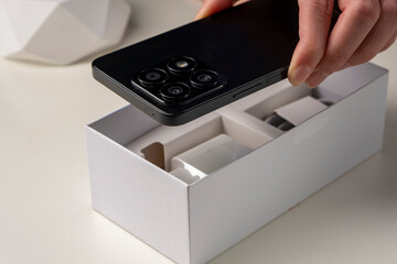 Unboxing a new smartphone. Female hands holding modern smartphone with blank screen. Online shopping, recent gadget concept