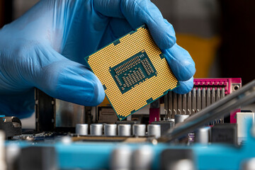 Gloved hand holding microprocessor near the motherboard.