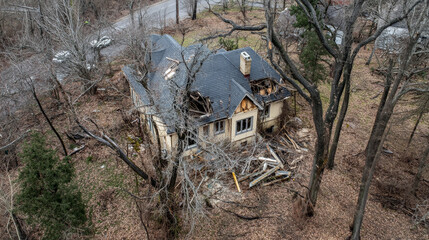 Aerial view of house with partially repaired roof surrounded by trees, showcasing signs of damage and neglect. scene evokes sense of abandonment and nature reclaiming space