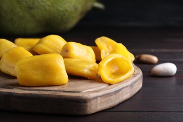 Fresh exotic jackfruit bulbs on black wooden table, closeup