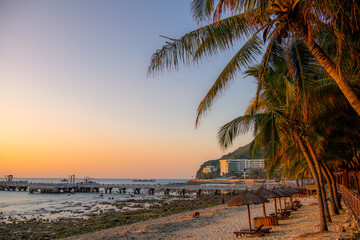 Daybeds and hotels in the morning light in Dadonghai beach in Sanya, Hainan, China