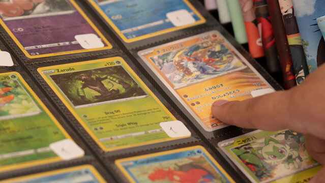 Budokan Geek Convention In GUAYAQUIL, ECUADOR - 
OCT 13, 2024 - Close-up of a person browsing through a collection of Pok&eacute;mon trading cards in a binder at a geek convention.