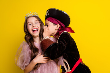 Photo of two little kids whisper ear laugh halloween pirate princess costume isolated on yellow color background © deagreez