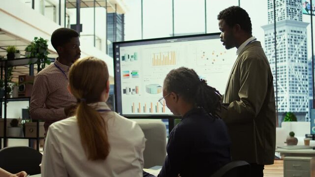 Team of company analysts reviews feedback on sales and orders to work on improvements, developing marketing and PR strategies in meeting room. Startup enterprise affiliates. Camera B.