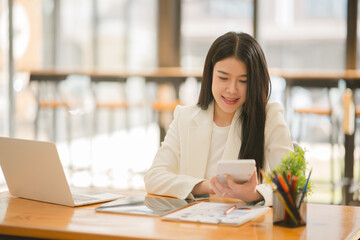 Asian business woman Use a calculator or laptop to make an accounting of income and expenses.  Monthly expenses