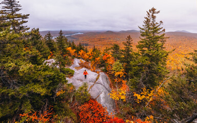 Female Hiker in Orange Jacket During Peak Fall Foliage Stands On Owl's Head Mountain Overlooking...