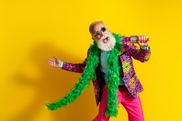 Portrait of overjoyed classy man sing microphone stage isolated on yellow color background