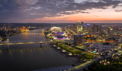 Aerial view of downtown district highway traffic in Cincinnati city, Ohio at night. Brightly illuminated high skyscraper buildings in modern American midtown