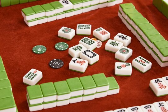 Woman in cheongsam playing mahjong(majiang), close-up, traditional Chinese mind game(Translation: mahjong terms, east, west, south, north, middle, fortune)