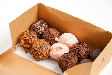 Small, round donuts coated with chocolate.Delicious homemade cookies in paper box on table, close-up