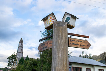 Weathered wooden direction sign indicating the direction of the cathedral and the costanera arturo