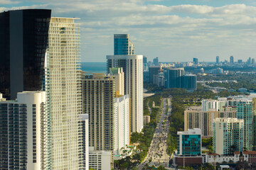 Obraz premium Sunny Isles Beach city with luxurious highrise hotels and condo buildings and busy ocean drive on Atlantic coast. American tourism infrastructure in southern Florida
