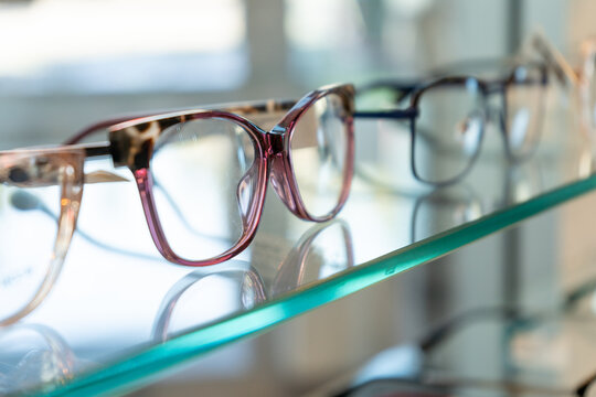 Closeup of purple eyeglasses frame on glass shelf in an optometry shop for prescription lens inserts