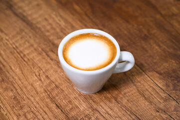 White cup of coffee with a wooden background