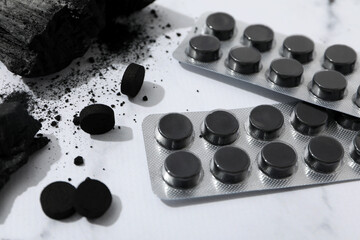 Activated carbon in the form of tablets, on a light background.