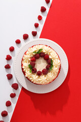 Red velvet cake on plate and berries on red and white background, top view