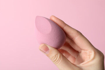 Makeup sponge in hand on pink background
