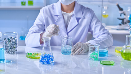 Photograph of science experiment concept, a female scientist sits by white lab table and stirs...