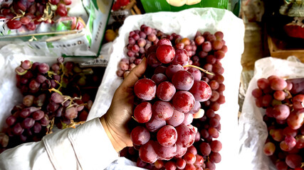 Close-Up of Hand Holding Fresh Red Grapes at Market