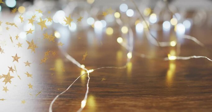 Golden stars animation over string lights on wooden surface