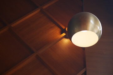 A contemporary modern pendant light fixture elegantly positioned against a rustic wooden ceiling