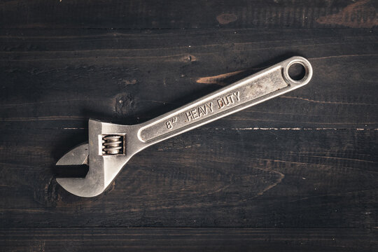 Adjustable wrench on wooden table. Heavy duty tool. Adjustable wrench on wooden table. Dark moody still life 