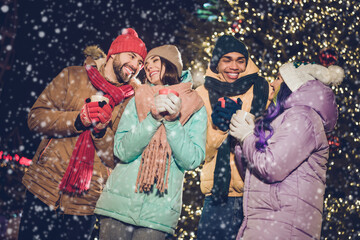Obraz premium Portrait of group peaceful cheerful fellows hold hot chocolate coffee cup have good mood evening magic outside