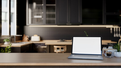 A close-up of a laptop mockup on a wooden kitchen tabletop in a modern, luxurious black kitchen.