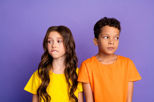 Photo of lovely two little kids shy nervous avoid eye contact dressed stylish orange yellow garment isolated on purple color background