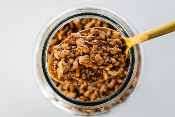 pantry staple close-up, spoonful of textured vegetable protein or dehydrated soy over clear glass...