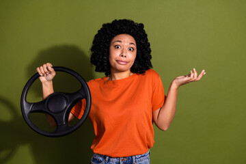 Portrait of nice young woman wheel shrug shoulder wear orange t-shirt isolated on khaki color...