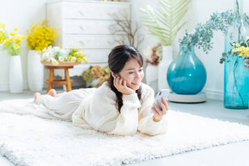 寝転びながら携帯を持ちリラックスする女性