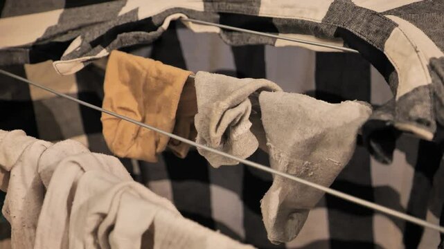 Close-up of a woman hanging socks to dry on an indoor laundry rack - 4K.