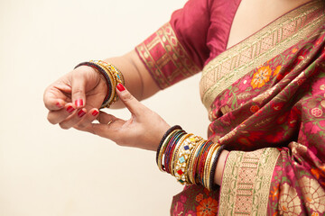 Fototapeta premium A traditional Indian woman wearing a saree adjusts her bangles during an Indian wedding ceremony.