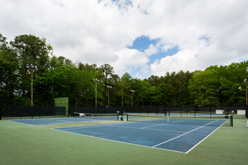 Tennis Courts With Green Surroundings And Clear Sky