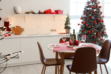 Interior of modern kitchen with festive table setting, Christmas tree and decor
