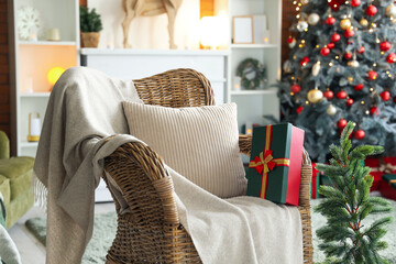 Interior of festive living room with wicker armchair, Christmas tree and gift box