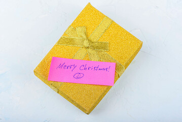 Gift wrapped in gold with a pink note saying Merry Christmas .