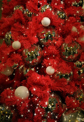 A Christmas tree with red branches and silver balls. Red Christmas background with mirrored sparkling balls. Christmas decor. Winter holiday theme. New Year celebration.