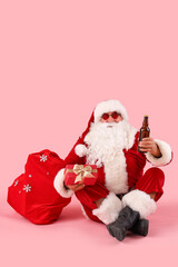 Santa Claus with beer and bag of gifts on pink background