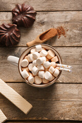 Cup of hot cocoa with marshmallows and sweet waffle on wooden background