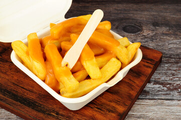 Chips and chip shop curry sauce in a take away box with wooden fork